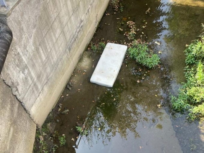 Gettano un materasso nel letto del torrente